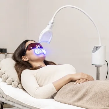 A client receiving a light-assisted teeth whitening treatment